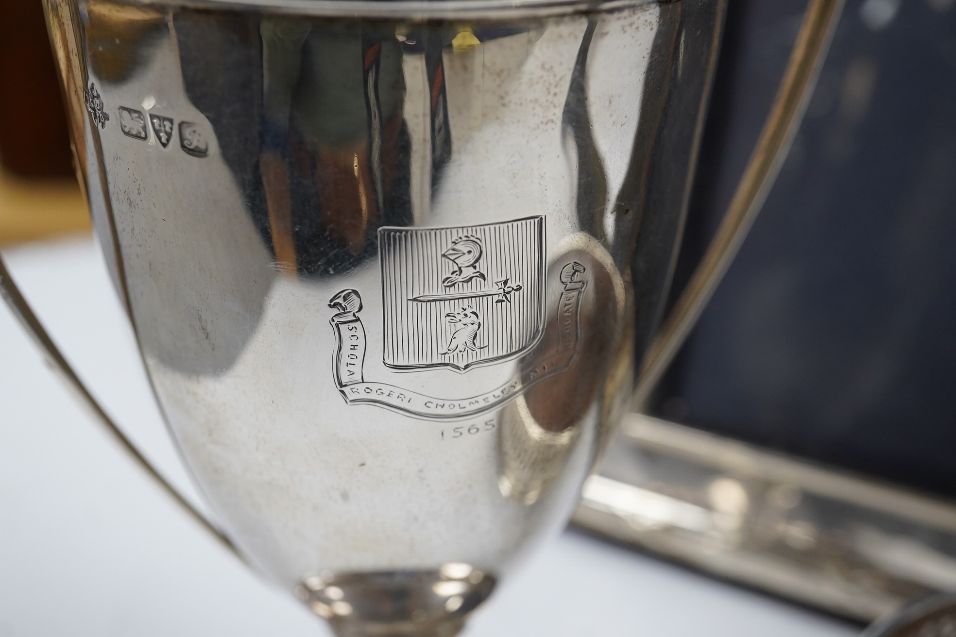 A George V silver two handled presentation trophy cup, 21.8cm, a modern silver wine coaster, a modern mounted silver photograph frame and a George V silver mounted photograph frame. Condition - poor to fair